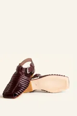 Sandalias planas tipo huarache de cuero negro, con tiras entrelazadas a mano y tira ajustable en el talón con hebilla metálica.