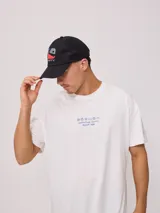 Gorra trucker Rusty con visera gris, frente blanco con logo estampado y malla trasera gris.