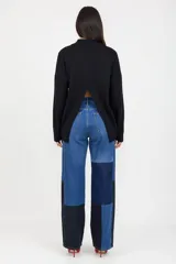 Pantalón de jean de corte recto y tiro alto, con diseño patchwork que combina diferentes tonos de denim azul y negro. Presenta bolsillos delanteros funcionales y cierre frontal con botón.