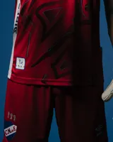 Short de arquero del Club Nacional de Football, temporada 2025. Diseño en color rojo con detalles en blanco y azul, confeccionado en tejido deportivo transpirable. Incluye el escudo del club bordado en la parte inferior.