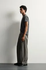 Jeans loose fit de hombre en denim de algodón color gris oscuro con efecto lavado. Presenta perneras con costuras giradas hacia los tobillos, tiro medio, cierre frontal con botones y bolsillos frontales con bolsillo cerillero.
