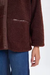 Campera de sherpa color marrón con cuello alto, cierre frontal con botones a presión y detalles en tela técnica a tono. Presenta un bolsillo vertical con cierre en el pecho y dos bolsillos laterales con cierre.