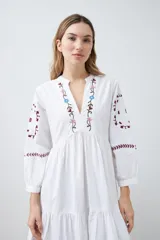 Vestido midi blanco con bordados de flores en el escote, mangas y ruedo.