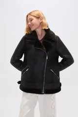Campera de estilo aviador confeccionada en eco-cuero negro con interior de piel sintética oscura. Presenta cierre frontal cruzado, solapas amplias, bolsillos laterales con cierre y detalles de hebillas ajustables en los puños.
