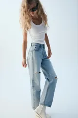 Jeans wide leg de tiro alto y cinco bolsillos, confeccionados en denim con lavado azul medio y efecto desgastado. Presenta cierre frontal con cremallera y botón metálico.