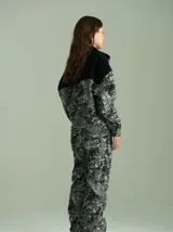 Campera de denim texturado con estampado abstracto en tonos grises y negros. Presenta un canesú superior en denim liso negro, cuello de piel sintética negra, cierre frontal con botones a presión color bronce y mangas largas.