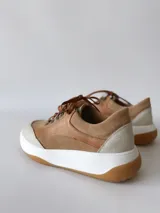 Zapatillas deportivas de cuero color camel con cordones marrones y suela blanca.