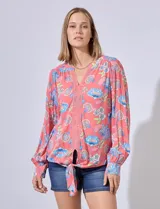 Blusa estampada con cuello a la base, escote en V y aplique de puntilla. Terminación de ruedo con nudo.