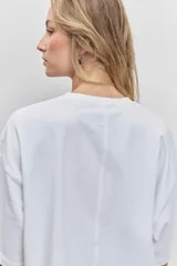 Remera blanca de corte oversize con cuello redondo y mangas cortas, presenta un pequeño bordado de cerezas en el pecho.