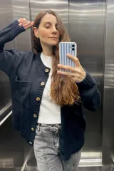 Saco tejido de lana color negro con botones marrones, de corte clásico y bolsillos frontales.