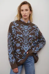 Buzo de tejido de punto en color marrón con un patrón ornamental floral en color celeste. Presenta cuello redondo, mangas largas y un corte holgado.