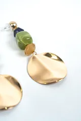 Aros colgantes dorados con diseño en cascada que incluye una esfera dorada superior, una cuenta facetada azul oscuro, una cuenta verde jaspeada, una cuenta facetada tostada y un gran dije circular metálico inferior con acabado ondulado.