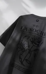 Remera de manga corta con cuello redondo y calce oversize, color gris oscuro. Presenta una estampa frontal con diseño gráfico de un escorpión y una rosa, junto con texto tipográfico.