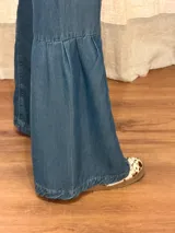 Jean de denim azul con bolsillos delanteros aplicados, costuras verticales y diseño de tablas en los laterales de las piernas amplias.