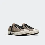 Championes Converse Chuck 70 de corte bajo, confeccionados en lona de color gris con estampado de estrellas. Presentan cordones negros, puntera de goma reforzada y entresuela barnizada en tono blanquecino con líneas negras decorativas.