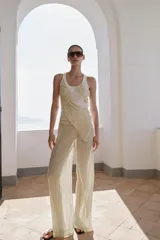 Pantalón de pierna ancha y tiro medio, confeccionado en tejido con textura arrugada. Presenta una cintura elástica destacada por un detalle de tejido en crochet a tono.