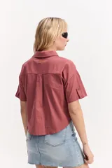Camisa de manga corta color rosado, con cuello camisero, bolsillos frontales con solapa, botones a tono y diseño ligeramente recortado.