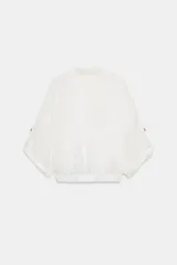 Blusa negra de cuello solapa y manga corta, con bolsillos con solapa en el pecho, bajo elástico y cierre frontal con botones.