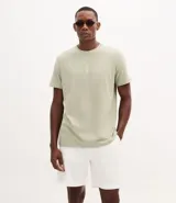 Remera de algodón color verde claro, de corte regular, cuello redondo y manga corta. Presenta un estampado náutico de un ancla y letras en el pecho.