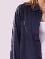 Camisa color verde oliva de lyocell, marca Cyrus. Tiene cuello con solapa, abertura central con botones, mangas 3/4 regulables con presilla y botón, y dos bolsillos delanteros aplicados.