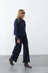 Jean de corte flare con tiro alto, confeccionado en denim azul oscuro. Presenta un ajuste entallado en la parte superior y una apertura progresiva hacia el bajo, con costuras a contratono que definen su estructura.