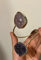 Brazalete rígido abierto de metal plateado con dos amatistas en bruto engarzadas en los extremos.