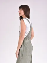 Monoprenda (jardinera) color verde oliva, de corte holgado y pierna ancha, con tirantes ajustables, cierre frontal de botones y lazo para ajustar en la cintura.