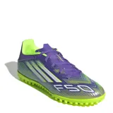 Championes de fútbol Adidas F50 Club para césped sintético, con diseño aerodinámico en tonos violeta y verde lima. Presenta cierre con cordones, suela con tapones pequeños para tracción y el logo F50 estampado en el frente.