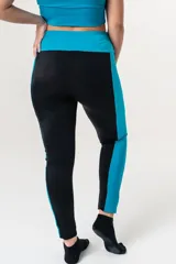 Calza deportiva de tiro alto con cintura elástica reforzada. Presenta un diseño bicolor que combina paneles laterales y faja con estampado animal print en tonos coral y turquesa sobre una base negra.