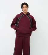 Pantalón de jogging color bordó con paneles laterales en negro y detalles de líneas blancas. Presenta un corte holgado y cintura elástica con cordón de ajuste.