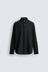 Camisa de corte relajado confeccionada en tejido ligero de lana y algodón. Presenta cuello con botones, manga larga con puños abotonados y cierre frontal de botones.