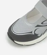 Championes de estilo híbrido entre jogging y Mary Jane, confeccionados en poliuretano. Presentan un diseño con cierre de tira adherente en el empeine, suela robusta y detalles en tonos grises y plateados.