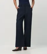 Pantalón de sastrería corte recto, color marrón, con cintura de tiro medio, trabillas largas y bolsillos traseros.