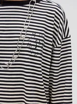 Remera manga larga a rayas horizontales grises y blancas, con cuello redondo rojo y logo bordado en el pecho. Corte holgado.