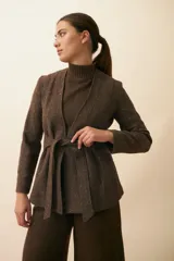 Chaqueta corta color beige, entallada, con escote en V, manga larga y bolsillos escondidos. Cierre frontal con lazo fijo. Confeccionada en lana fina sin teñir. Diseño exclusivo de Don Baez.