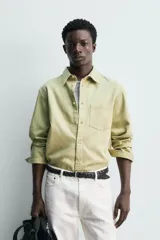 Camisa de corte regular fit confeccionada en denim ligero con mezcla de lyocell, algodón y lino. Presenta cuello solapa, cierre frontal de botones, manga larga con puños abotonados y un bolsillo en el pecho.