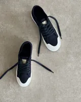 Zapatillas urbanas de lona color beige con cordones blancos y suela de goma blanca con diseño geométrico.