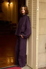 Campera de cuello alto con cierre frontal oculto, mangas largas abullonadas y diseño holgado, con bordados florales en el lateral. Color violeta oscuro.
