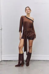 Vestido corto de satén color marrón, con diseño de un solo hombro y detalle de encaje negro en el escote y el ruedo. Presenta un nudo frontal con caída de tela y mangas largas.
