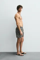 Short de baño largo con estampado geométrico en tonos oscuros sobre fondo claro, cintura elástica ajustable con cordón y bolsillos laterales.