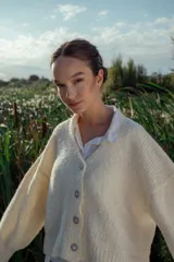 Cárdigan tejido en boucle color crudo, de corte holgado y mangas largas.