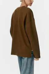 Buzo oversized de algodón con efecto lavado, cuello redondo acanalado y hombros caídos. Presenta costura decorativa en la espalda y aberturas laterales en el bajo.