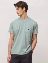 Camiseta de algodón orgánico con efecto lavado, cuello redondo, manga corta y bolsillo frontal en el pecho con etiqueta tejida con logo.