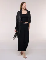 Pashmina rectangular negra con diseño jacquard de rombos, destellos metalizados dorados y flecos anudados en los extremos.