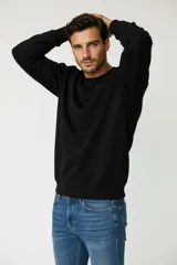 Sudadera de cuello redondo en color negro, con puños y cintura acanalados. Presenta un diseño minimalista con un pequeño logo bordado en el pecho.