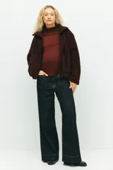 Campera de sherpa color bordó, con cuello alto, cierre frontal y bolsillos de parche. Diseño de hombros caídos y sin forro.