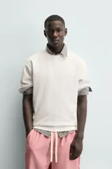 Camiseta blanca de corte relajado (relaxed fit) con cuello redondo y manga corta. Presenta un estampado grande en la espalda que simula dados rojos con letras y corazones.