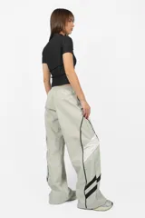 Pantalón deportivo gris de calce recto y tiro medio, con cintura elástica y cordones. Presenta recortes con vivos a contratono en los laterales y una estampa en el lateral izquierdo.