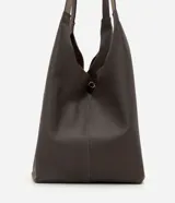 Cartera hobo grande marca Satinato, confeccionada en cuero con textura natural y color marrón oscuro. Presenta un diseño amplio y suave de estilo contemporáneo, con asas de hombro integradas y cierre interno con mosquetón.