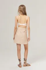 Minifalda de cuero color beige, de corte en A, cintura alta, cierre lateral y bolsillos traseros.